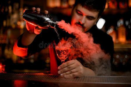 干冰盘酒吧间销售酒精饮料的人使用摇动者向准备一乙醇鸡尾酒照片